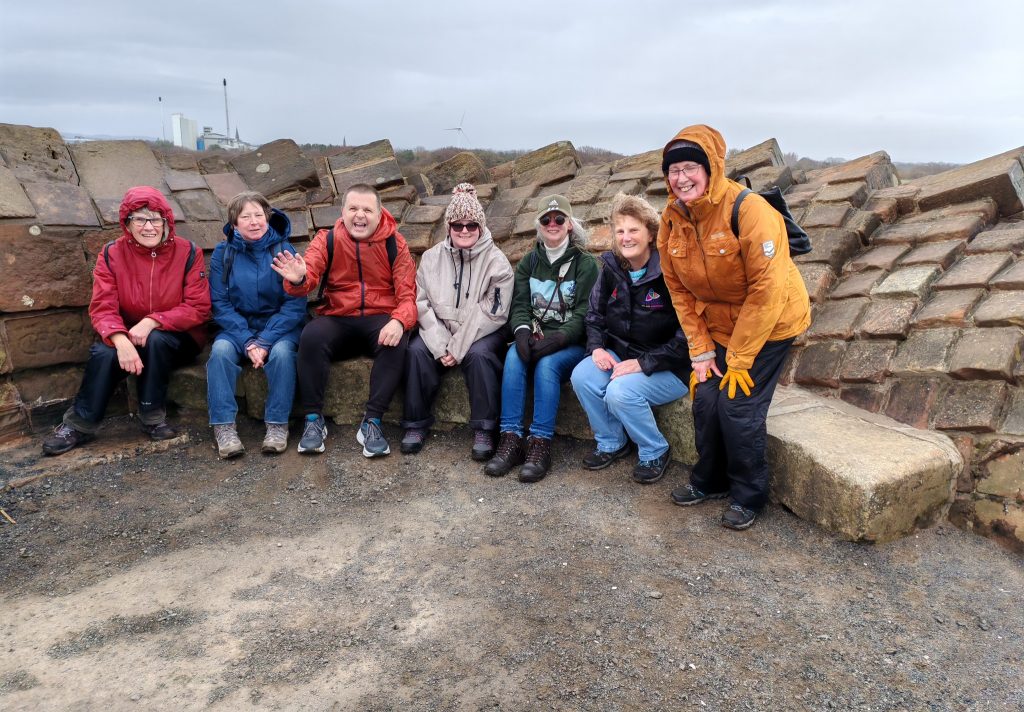 people sitting by a stone wall